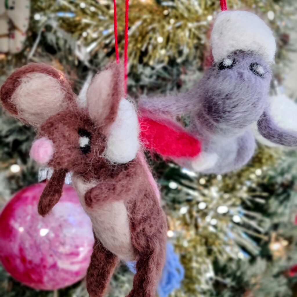 Homemade Christmas decorations: a mouse and a manatee both wearing Santa hats made using needle-felting techniques